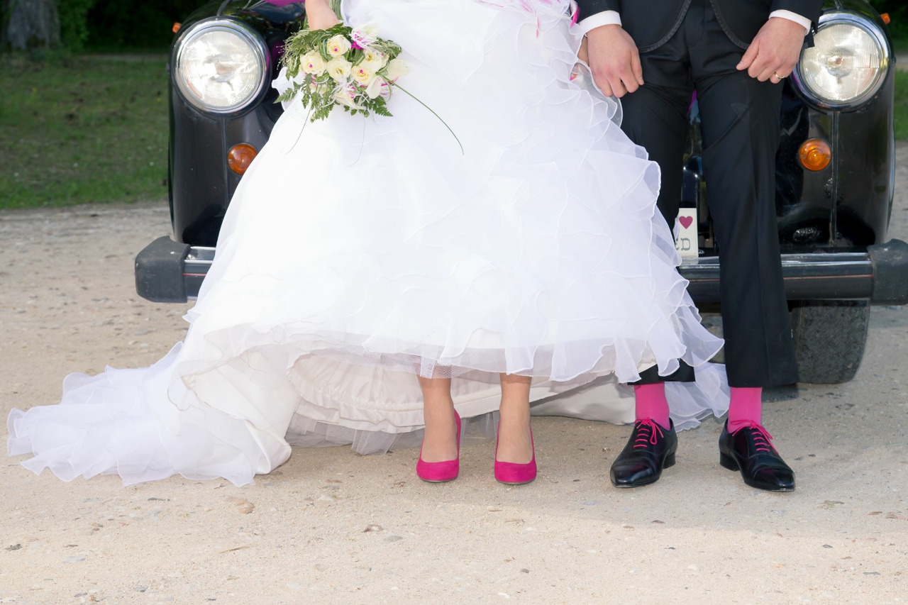 souliers et chaussettes et laces fuchsia les mariés assortis à la couleur de la décoration de leur voiture de mariage taxi anglais noir devant lequel ils posent