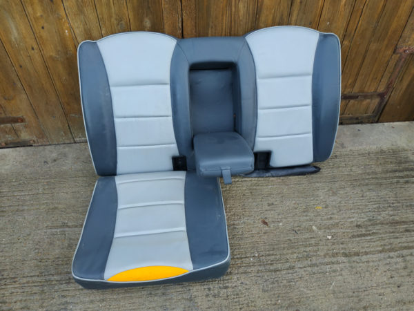 siege arriere taxi anglais tx1 tx2 bicolor presnte sur sol en beton devant porte garage en bois