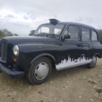 taxi anglais avec frise de londres en autocollant sur les cotes vue devant gauche