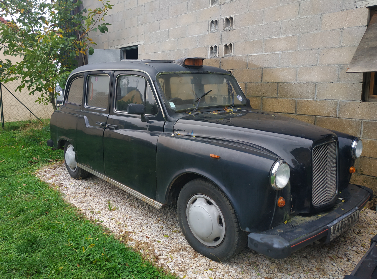 taxi anglais noir fairway devant un mur en parepaings
